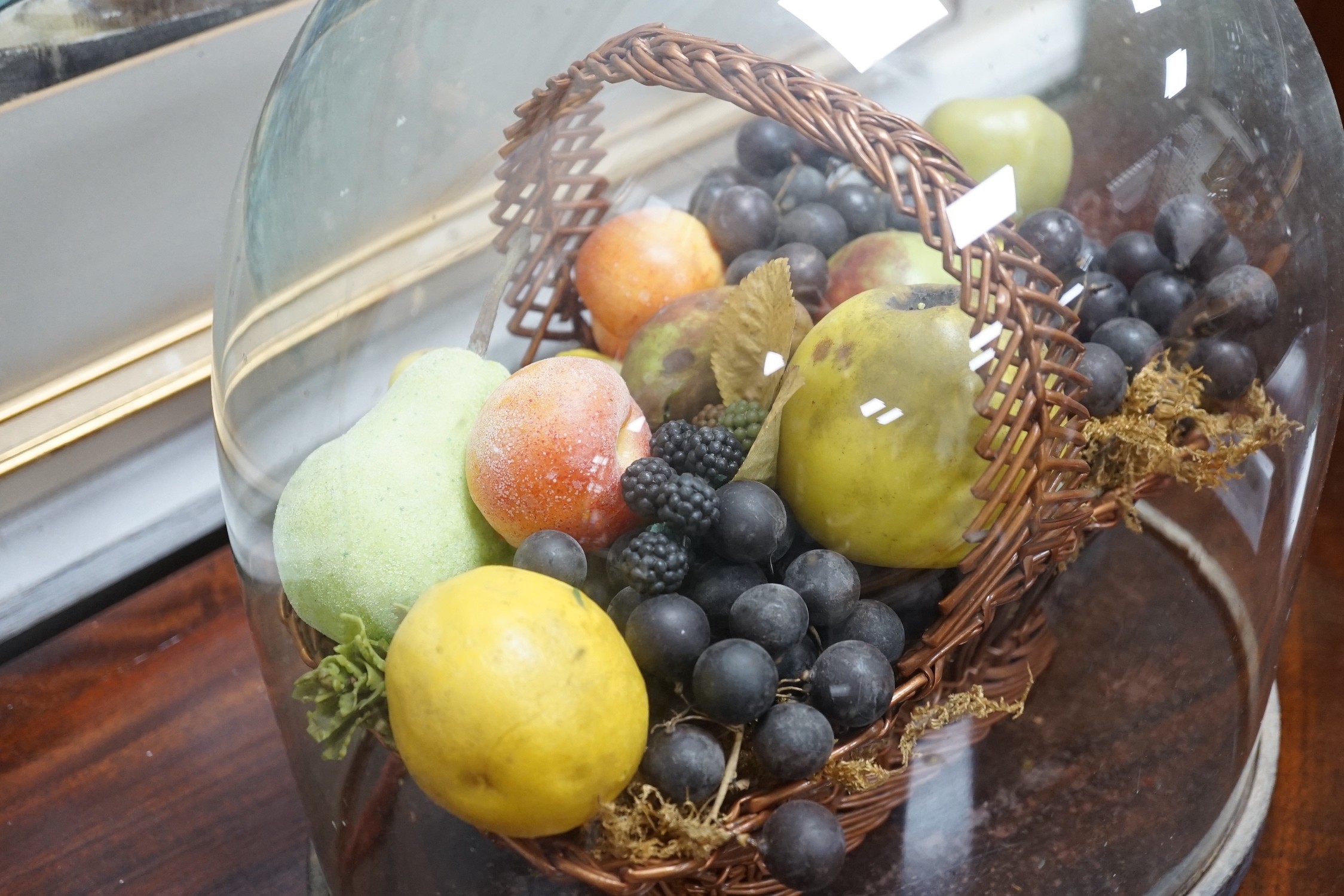 A Victorian wax fruit arrangement in a basket under glass dome, 34cms high